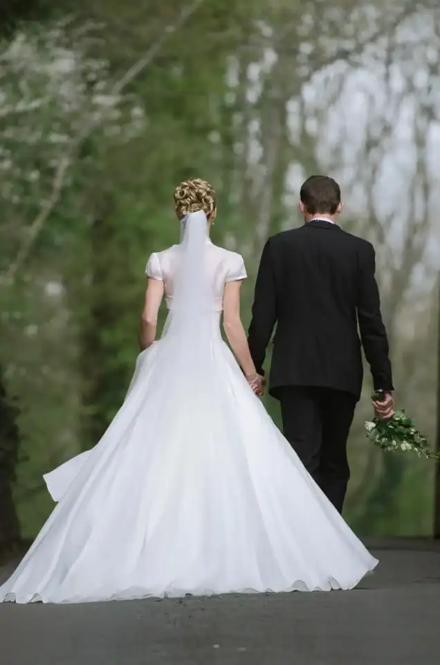 Lucy & Michael 15 Bride and groom hold hands whilst walking down the road near countryside - Scott Gilbert Wedding Photography