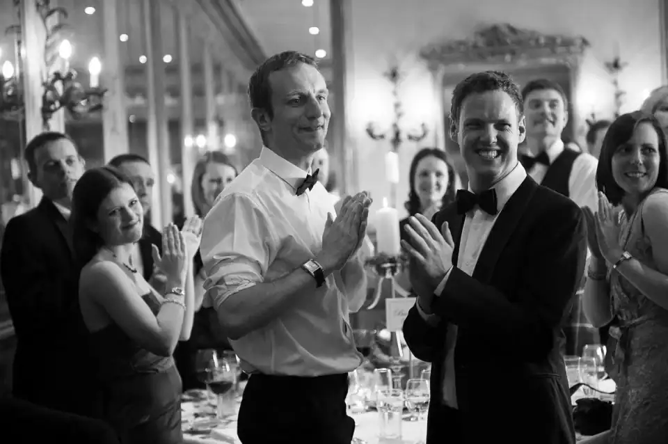 Lucy & Michael 3 Wedding guests clap at the reception as newly weds enter - Scott Gilbert Wedding Photography