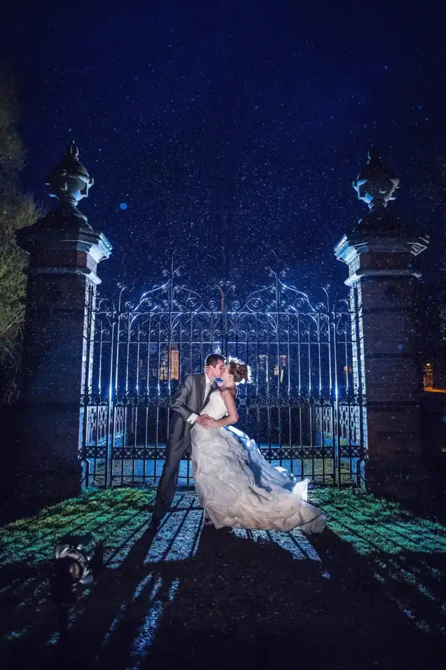 Married couple kiss outside iron gates in the rain - Scott Gilbert Wedding Photography