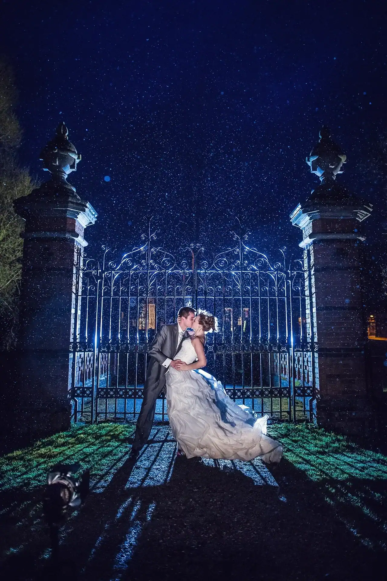 Married couple kiss outside iron gates in the rain - Scott Gilbert Wedding Photography