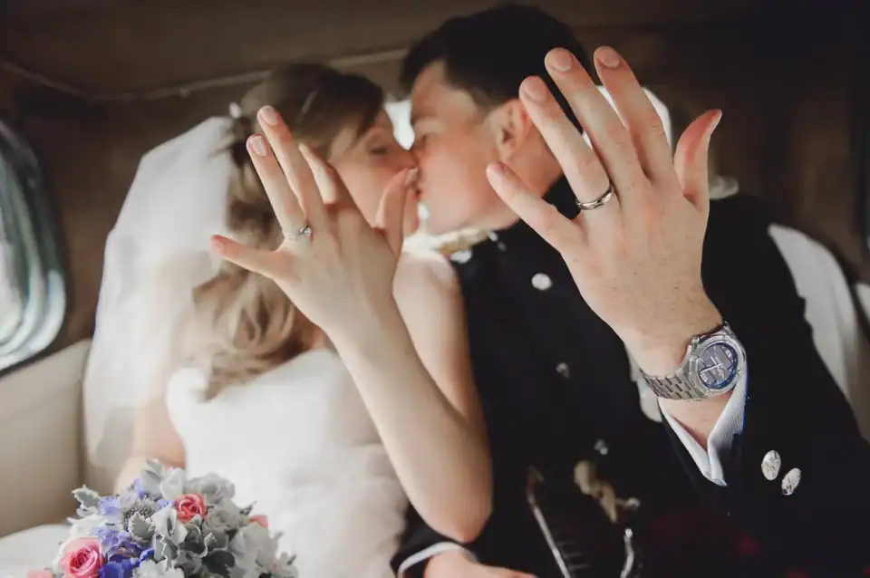 Bride and groom show off their wedding rings in the back of wedding car - Scott Gilbert Wedding Photography