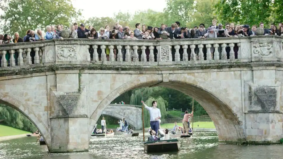 Wedding guests watch married couple from an old bridge ride past on a punt in cambrdge - Scott Gilbert Wedding Photography