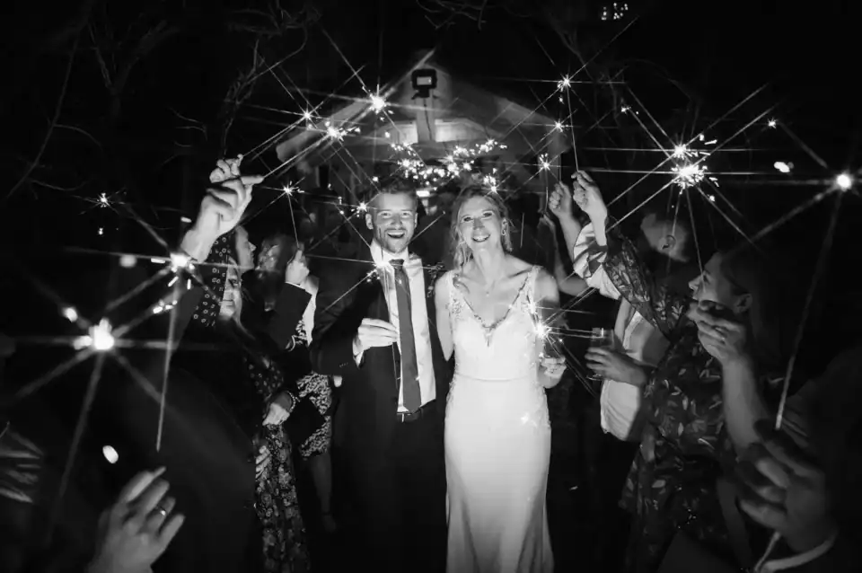Bride and groom walk through parade of guests with sparklers - Scott Gilbert Wedding Photography