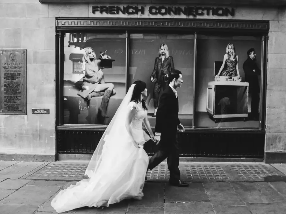 Newly weds walk past designer clothing shop in Cambridge town centre - Scott Gilbert Wedding Photography