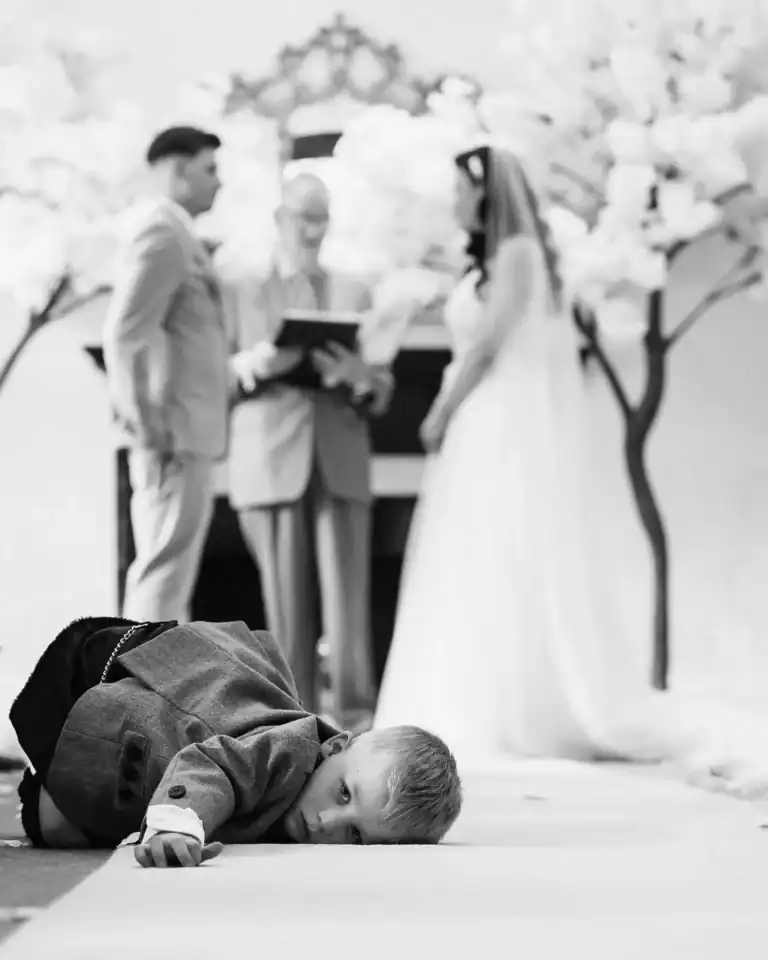 Young page boy takes a rest during wedding ceremony - Scott Gilbert Wedding Photography