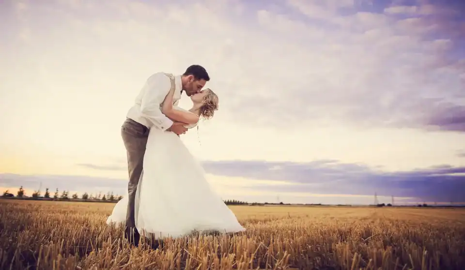 Bride and groom kiss in countryside field - Scott Gilbert Wedding Photography