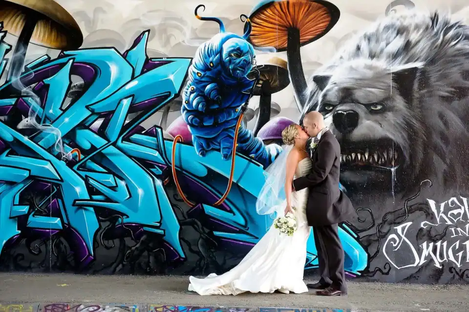 Bride and groom share a kiss in front of Alice in Wonderland graffiti wall - Scott Gilbert Wedding Photography