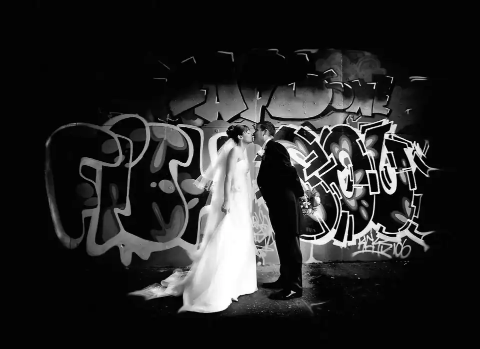 Couple share a kiss in front of graffiti wall - Scott Gilbert Wedding Photography