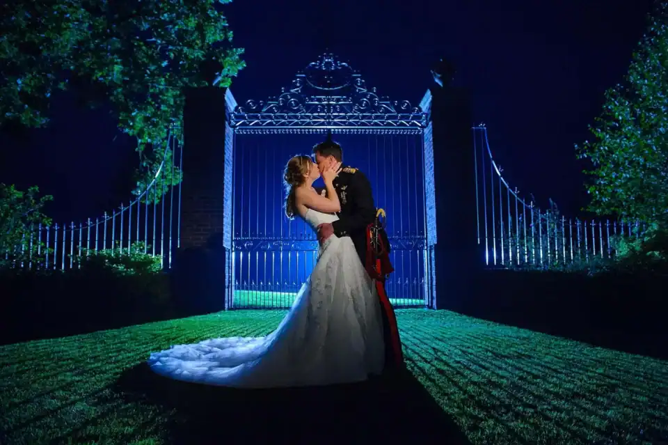 Newly married couple kissing at night in front of manor gates - Scott Gilbert Wedding Photography