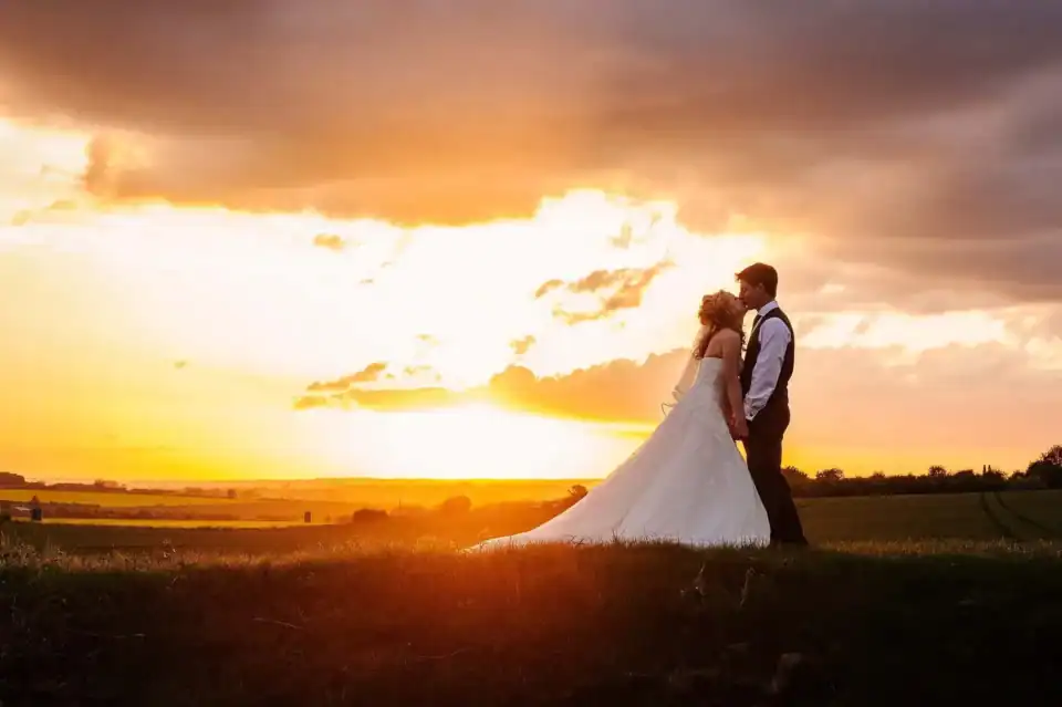 Bride and Groom kiss in field in Hertfordshire after their wedding with beautiful sunset - Scott Gilbert Wedding Photography